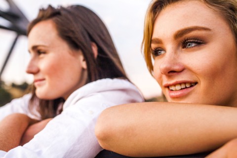 Caucasian teenage girls leaning on banister together