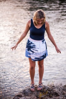 Caucasian teenage girl standing on rocky riverbank
