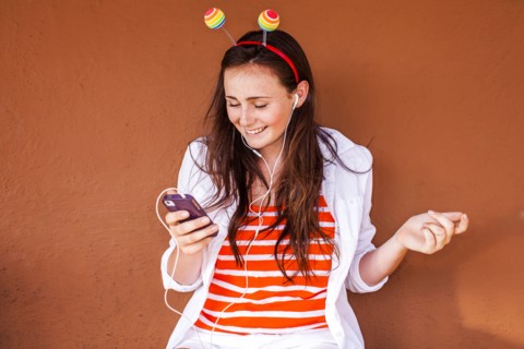 Caucasian woman in novelty antenna listening to mp3 player