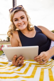 Caucasian teenage girl using tablet computer in park