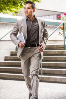 Hispanic businessman carrying digital tablet near staircase