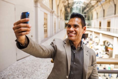 Hispanic businessman taking cell phone picture on upper level
