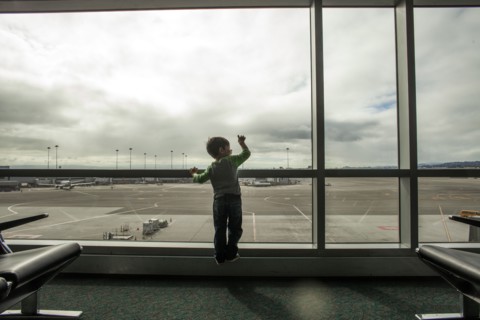 Mixed race boy looking out airport window