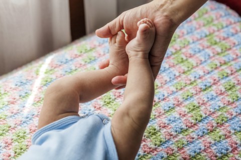 Mother holding feet of baby boy