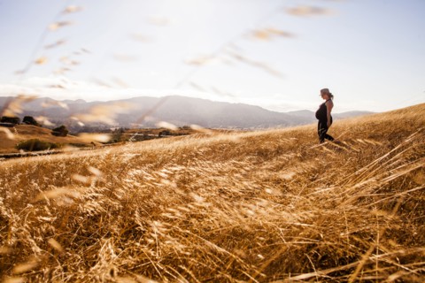 Pregnant Caucasian woman walking in rural meadow