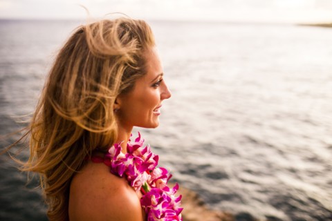 Caucasian woman wearing flower lei by ocean
