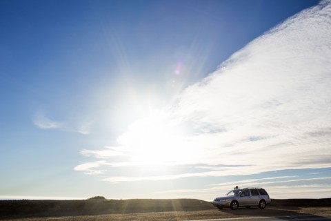 Sunshine and clouds over car on roadside