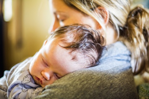 Caucasian mother holding sleeping baby son