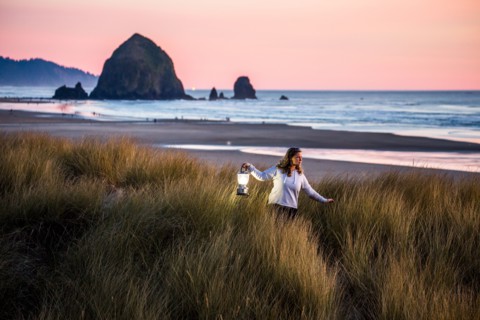Caucasian woman carrying lantern on Cannon Beach
