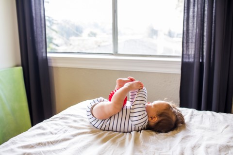 Caucasian baby girl playing on bed