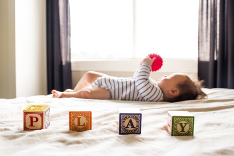 Caucasian baby girl playing on bed