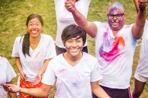 Smiling friends covered in pigment powder cheering