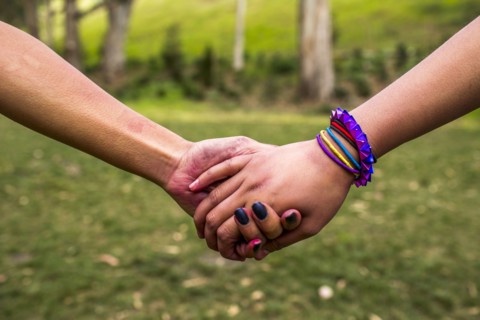 Close up of women holding hands in park