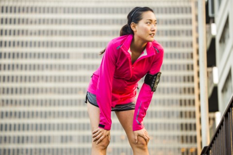 Runner resting near highrise building