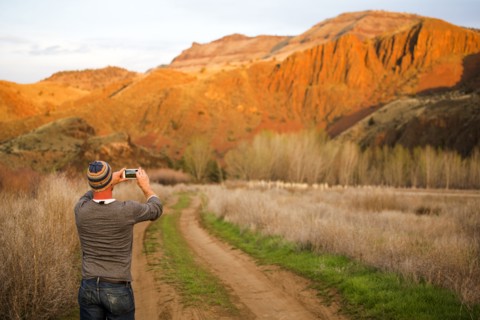 Caucasian man photographing desert hills