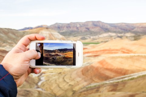 Caucasian man taking cell phone photograph of desert landscape