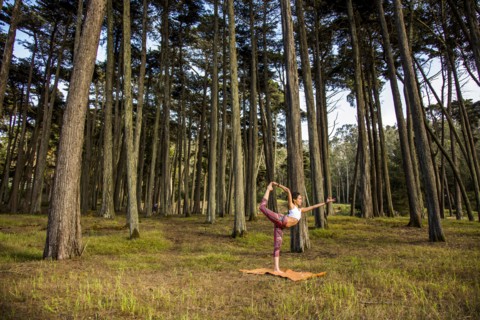 Hispanic woman practicing yoga in forest
