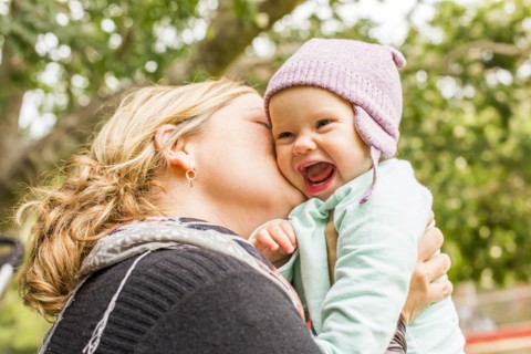 Caucasian mother kissing baby daughter outdoors