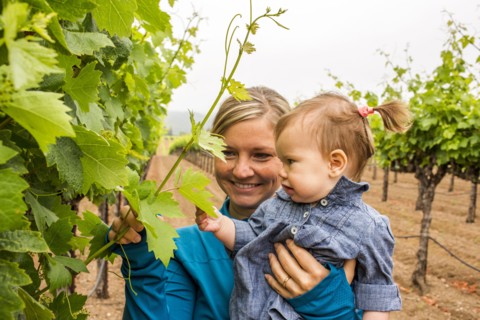 Caucasian mother and daughter admiring vine in vineyard
