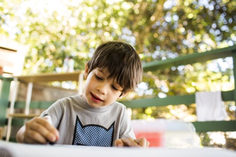 Mixed race boy coloring on porch