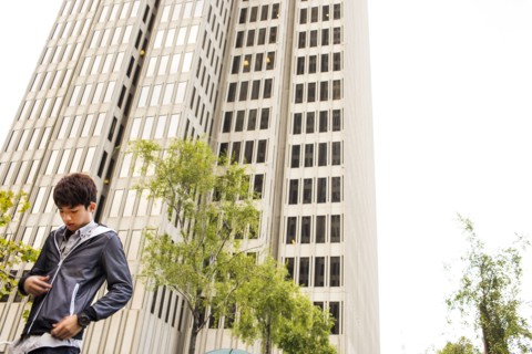 Asian man standing near urban skyscraper