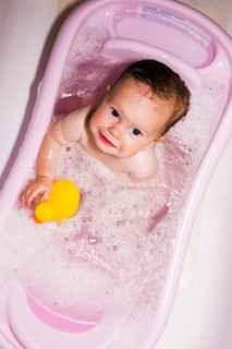 Caucasian baby girl sitting in bathtub