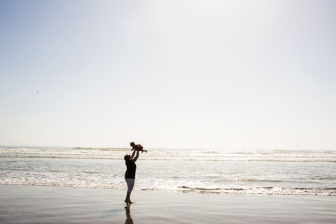 Caucasian mother lifting baby daughter on beach
