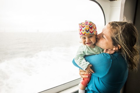 Caucasian mother kissing baby daughter at window