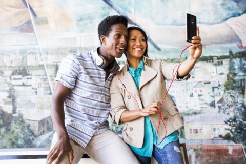 Couple taking selfie with digital tablet by mural