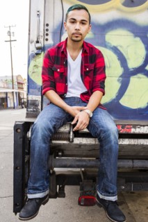 Hispanic man sitting on graffiti truck