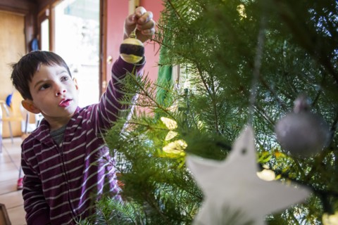 Mixed race boy decorating Christmas tree