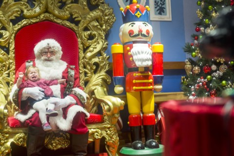Caucasian girl sitting on lap of Santa and crying