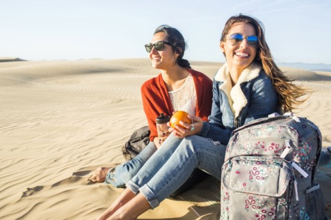 Mixed race women sitting on sand dunes