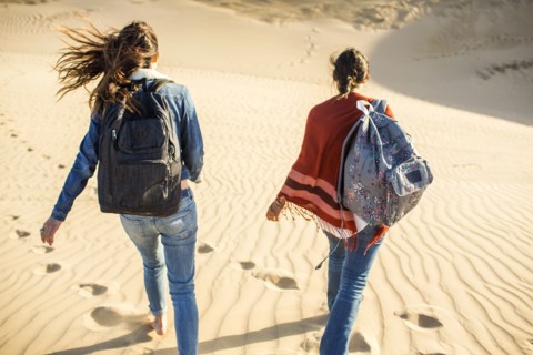 Mixed race women walking on sand dunes
