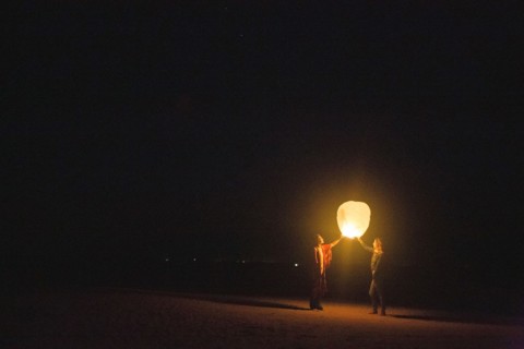 Mixed race women flying lantern at night