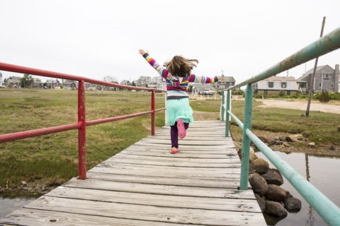 Carefree Caucasian girl running on wooden footbridge