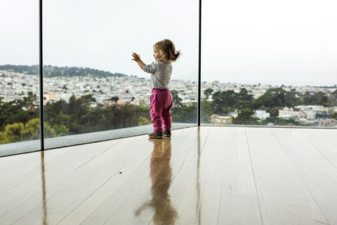 Curious Caucasian girl leaning on window admiring cityscape