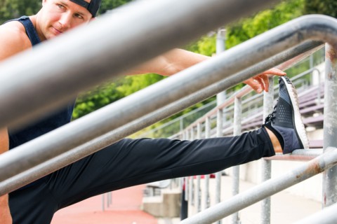 Caucasian man stretching leg at running track