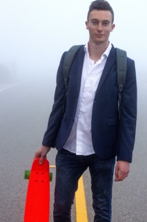 Caucasian man holding small red skateboard in fog