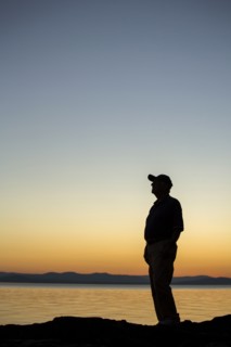 Silhouette of Caucasian man near water at sunset