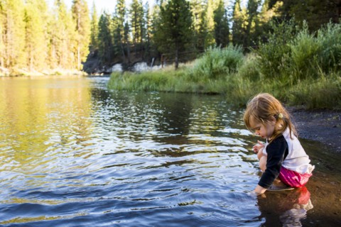Caucasian girl crouching in river