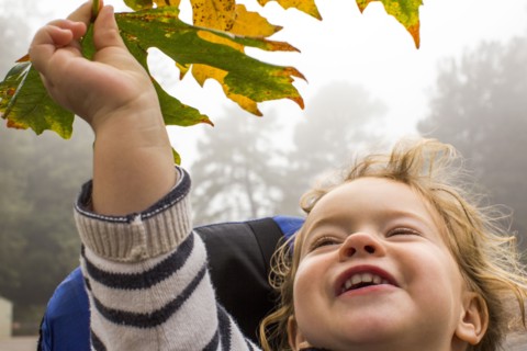Smiling Caucasian girl holding autumn leaf