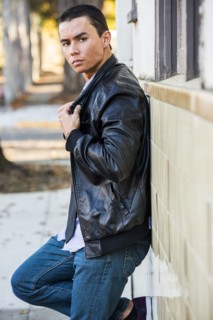 Serious Mixed Race man leaning on wall wearing leather jacket