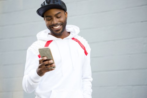Smiling Black man texting on cell phone
