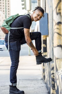 Androgynous Mixed Race woman carrying backpack adjusting boot