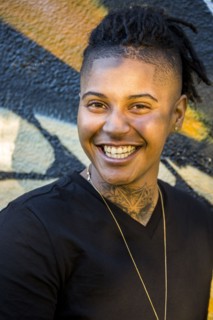 Portrait of androgynous Mixed Race woman smiling near graffiti wall