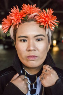 Portrait of serious androgynous Asian woman with flowers in hair