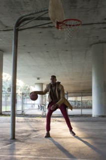 Black man wearing backpack playing basketball under overpass