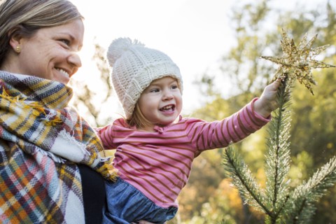 Caucasian mother helping daughter place star on top of Christmas tree
