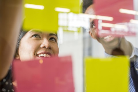 Woman and man reading adhesive notes in office